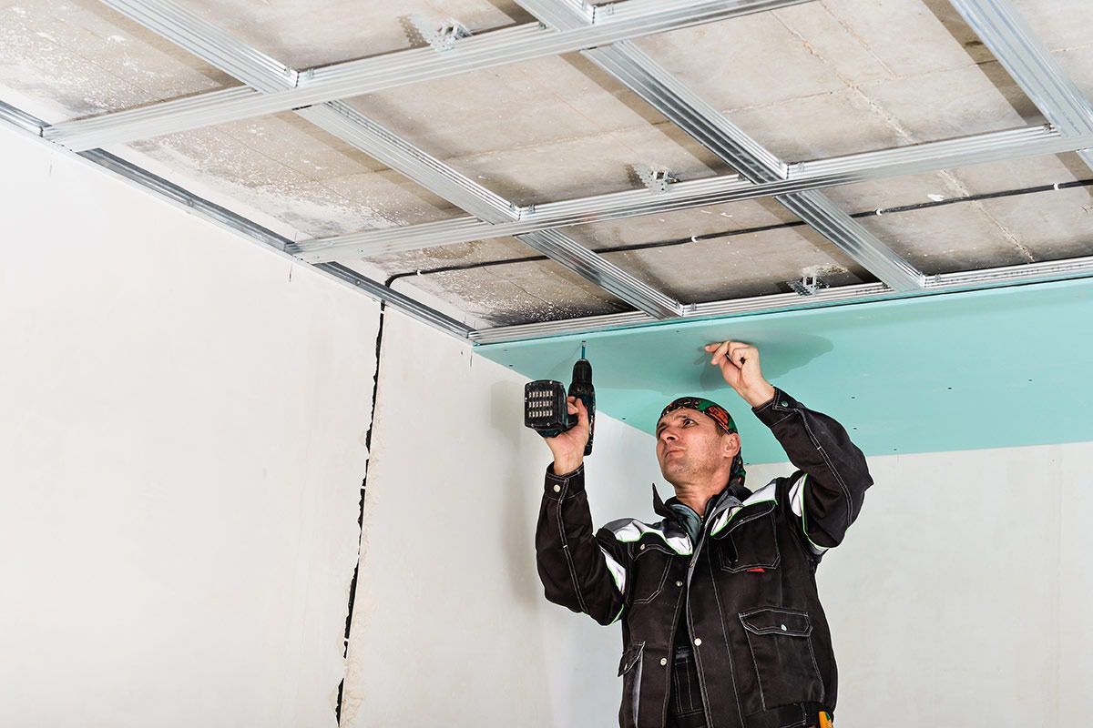Rats dans un faux plafond pro : diagnostic et remise en état 3 plâtrier remplaçant une dalle de faux plafond contaminée